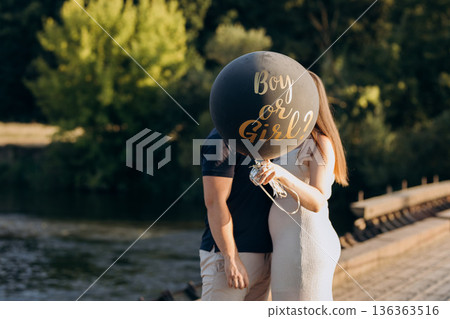 Couple holding Boy or Girl balloon at gender reveal, expecting baby outdoors Couple holding Boy or Girl balloon at gender reveal, expecting baby outdoors 136363516