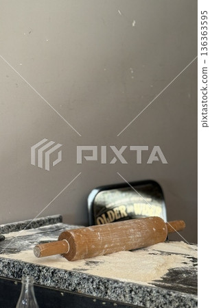 Rolling pin on flour-dusted countertop creates rustic baking background with empty space 136363595