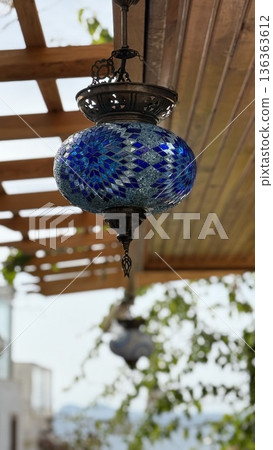 Turkish mosaic lantern with vibrant blue pattern hanging outdoors under wooden pergola background Turkish mosaic lantern with vibrant blue pattern hanging outdoors under wooden pergola background 136363612