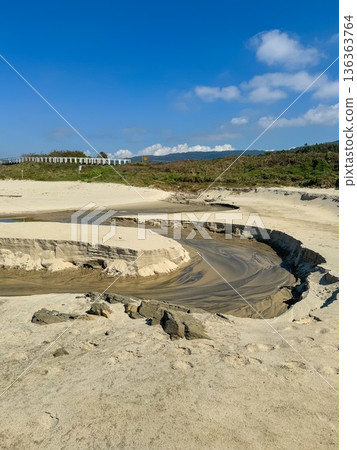 Sandy coastal landscape with shallow stream carving curved channel through beach near Atlantic shoreline along Camino de Santiago. Tourism marketing, coastal geography, environmental education 136363764