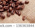 Cracked roasted coffee beans scattered on coarse textured burlap fabric. Aromatic caffeine beverage concept. 136363844