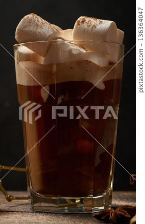 A glass of hot chocolate or cocoa with lots of cinnamon-dusted marshmallows on a dark background. A cozy winter drink. A glass of hot chocolate or cocoa with lots of cinnamon-dusted marshmallows on a dark background. A cozy winter drink. 136364047
