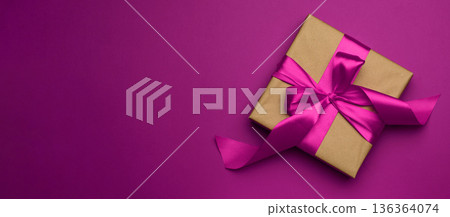Square gift box is packed in paper and curled silk ribbon on a pink background, festive background Square gift box is packed in paper and curled silk ribbon on a pink background, festive background 136364074