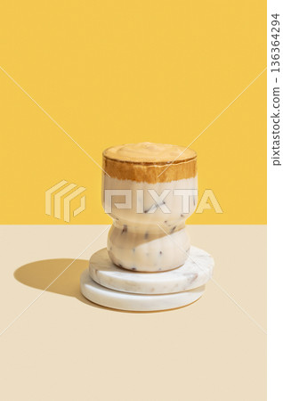 Dalgona coffee on a marble stand on a yellow background with shadow. Korean whipped drink 136364294
