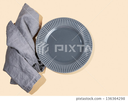 A ceramic dark gray plate with a napkin on a yellow isolated background. 136364298