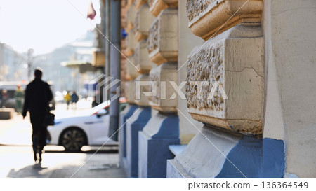 Urban scene with blurred pedestrian walking past building facade detail Urban scene with blurred pedestrian walking past building facade detail 136364549