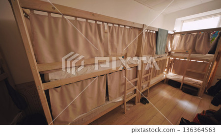 Hostel dormitory with bunk beds and privacy curtains, offering shared accommodation 136364563
