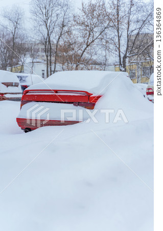 Snow covered car parked outdoors after heavy snowfall with thick snowdrift surrounding vehicle on urban parking. Concept of snow winter weather, cold season, transport issue, climate, parking problem Snow covered car parked outdoors after heavy snowfall with thick snowdrift surrounding vehicle on urban parking. Concept of snow winter weather, cold season, transport issue, climate, parking problem 136364869