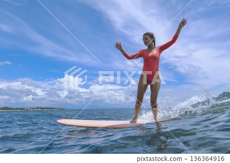 Lively Woman Skillfully Maintains Stance On Surfboard Amid Stormy Sky 136364916
