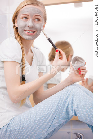 Woman applying with brush clay mud mask to her face Woman applying with brush clay mud mask to her face 136364961