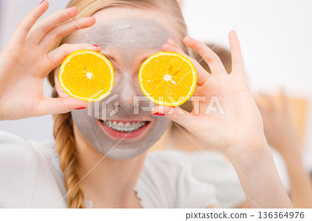 Happy young woman having face mask holding kiwi Happy young woman having face mask holding kiwi 136364976