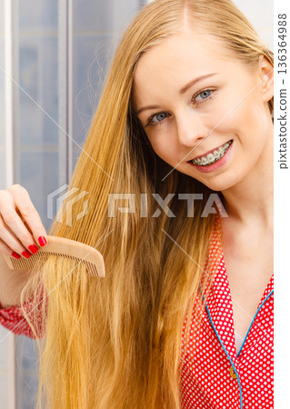 Woman combing her long hair in bathroom 136364988