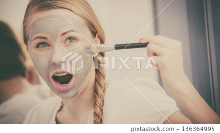Woman applying with brush clay mud mask to her face Woman applying with brush clay mud mask to her face 136364995