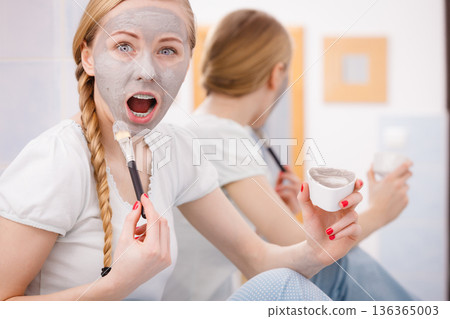 Woman with grey clay mud mask on her face Woman with grey clay mud mask on her face 136365003