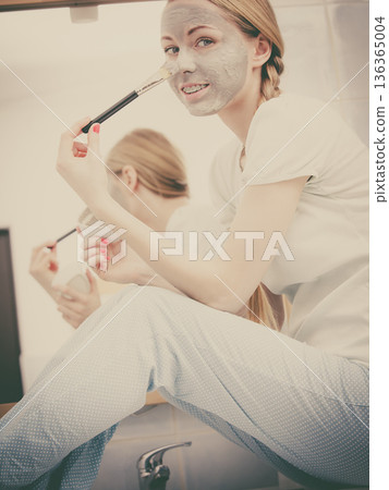 Woman applying with brush clay mud mask to her face Woman applying with brush clay mud mask to her face 136365004