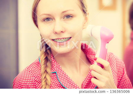 Woman using facial cleansing brush on face 136365006