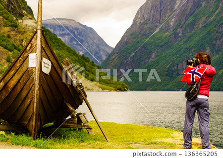 Tourist with camera near old viking boat, Norway 136365205