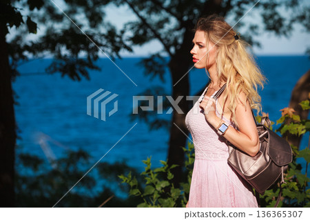 Casual girl with backpack on sea coast 136365307