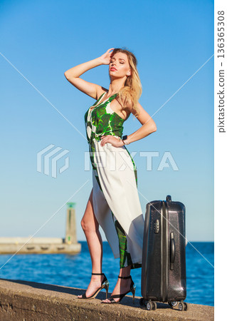 Woman with suitcae on city street 136365308