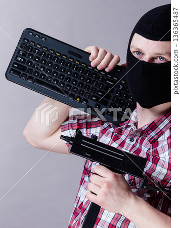 Man in balaclava holding keyboard and gun 136365487