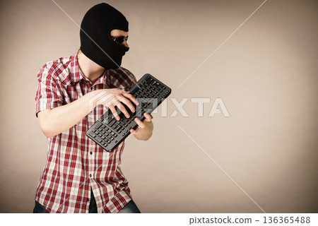 Man wearing balaclava holding keyboard 136365488