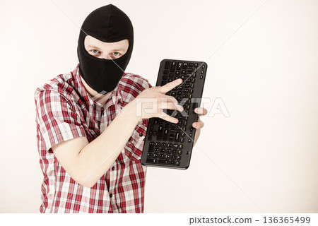 Man wearing balaclava holding keyboard 136365499