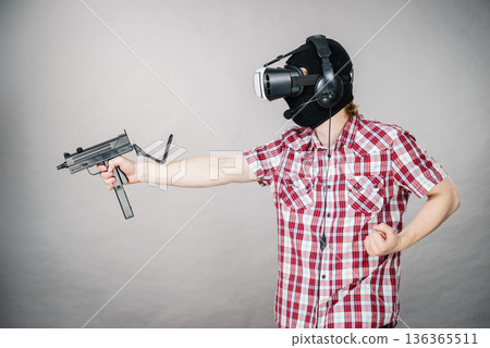 Gamer man wearing VR holding gun Gamer man wearing VR holding gun 136365511