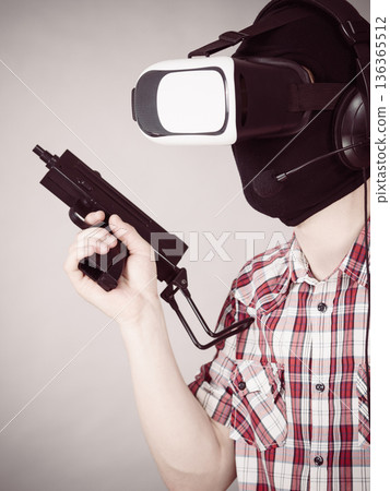 Gamer man wearing VR holding gun Gamer man wearing VR holding gun 136365512
