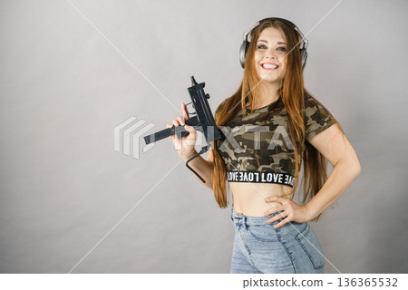 Woman wearing headphones holding gun 136365532