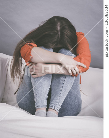 Worried woman sitting on sofa 136365534