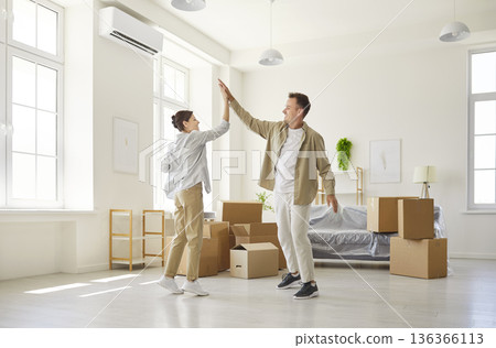 Happy couple moving into new apartment, giving high five to celebrate relocation Happy couple moving into new apartment, giving high five to celebrate relocation 136366113