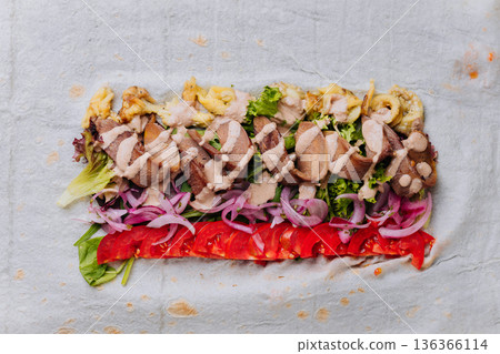 Open pork shawarma wrap with tomatoes, pickled onions and sauce, top view Open pork shawarma wrap with tomatoes, pickled onions and sauce, top view 136366114
