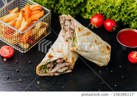 Pork shawarma wraps with fries and ketchup sauce on black table, close up Pork shawarma wraps with fries and ketchup sauce on black table, close up 136366117