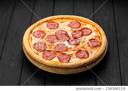 Pepperoni pizza on wooden board over dark rustic table, top view 136366119