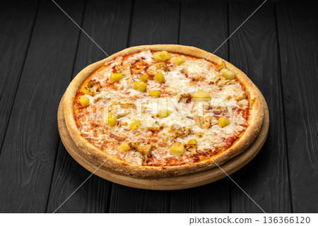 Chicken pineapple pizza with melted mozzarella on wooden board, dark background Chicken pineapple pizza with melted mozzarella on wooden board, dark background 136366120