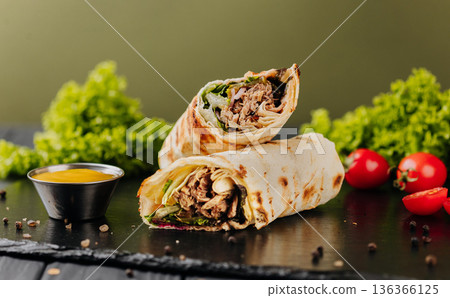 Grilled tuna tortilla wraps with greens, sauce and tomatoes on slate 136366125