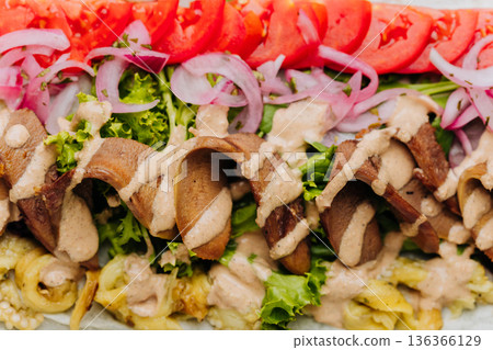 Open pork shawarma wrap with tomatoes, pickled onions and sauce, top view 136366129