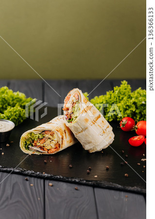 Grilled salmon tortilla wraps with avocado sauce and fresh greens on black slate 136366133