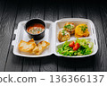 Takeaway lunch box with tomato soup, salad and cutlets on dark wooden table 136366137