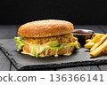 Crispy chicken burger with lettuce and melted cheese sauce, fries and ketchup , dark background 136366141