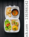 Takeaway lunch box with tomato soup, salad and cutlets on dark wooden table 136366142