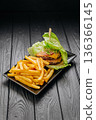 Bunless beef burger in lettuce wrap with fries on black plate, copy space 136366145