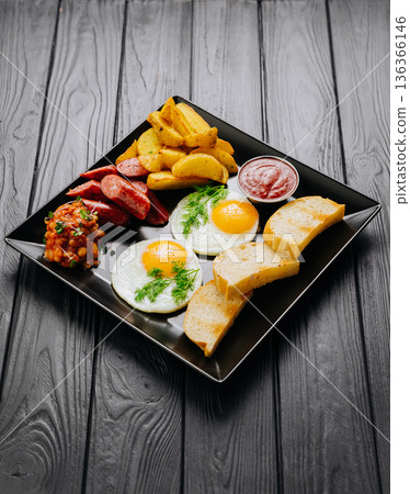 Breakfast plate with fried eggs, sausage, potato wedges and bread, top view Breakfast plate with fried eggs, sausage, potato wedges and bread, top view 136366146