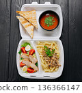 Takeaway meal box with tomato soup, toasted bread, creamy pasta and chicken salad 136366147