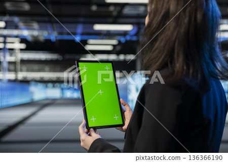Isolated screen tablet used by data center manager to review equipment diagnostics. Employee in server room using mockup notebook to adjust configurations, applying firmware updates, close up 136366190