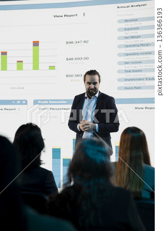 Professional businessman on stage delivering motivational speech during business conference event. Professionals and white collar workers attending international summit in auditorium. Professional businessman on stage delivering motivational speech during business conference event. Professionals and white collar workers attending international summit in auditorium. 136366193