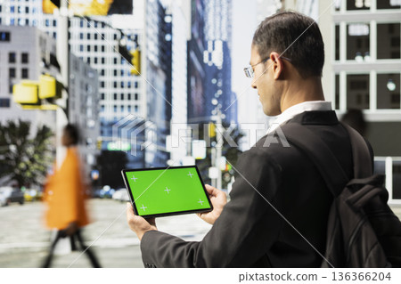 Horizontal chroma key on tablet held by indian man near other pedestrians, navigating crowded avenue with active motion. Diverse community lifestyle and dynamic pace of a metropolis. Horizontal chroma key on tablet held by indian man near other pedestrians, navigating crowded avenue with active motion. Diverse community lifestyle and dynamic pace of a metropolis. 136366204