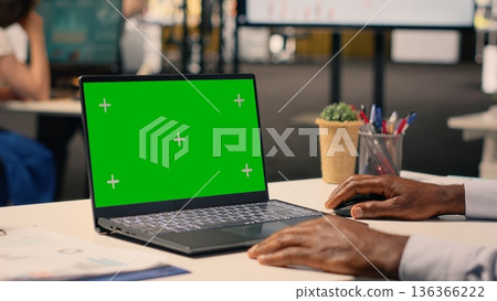 Green screen mockup with black man sitting at business office desk, corporate lifestyle image of daily tasks. Forecasting reports and analytics dashboard support strategic planning and goals. Green screen mockup with black man sitting at business office desk, corporate lifestyle image of daily tasks. Forecasting reports and analytics dashboard support strategic planning and goals. 136366222