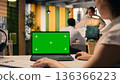 Green screen laptop, woman at desk, multinational company office, employee working, KPI metrics, and visual data. Analytics and insights, organizational planning, business intel. 136366223
