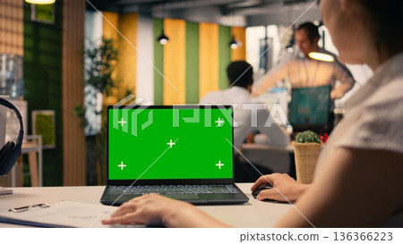 Green screen laptop, woman at desk, multinational company office, employee working, KPI metrics, and visual data. Analytics and insights, organizational planning, business intel. 136366223